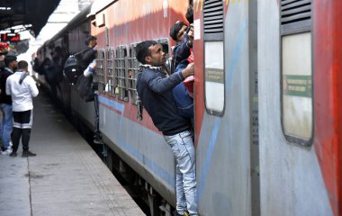 GHAZIABAD, INDIA - 17 Şubat 2025 'te Ghaziabad, Hindistan' da Ghaziabad Junction tren istasyonundaki kalabalık birbirlerini trene binmeye ve hareket halindeki trene tutunmaya zorluyor.. 