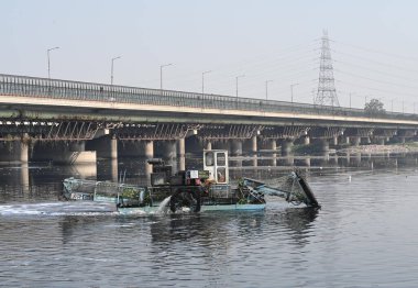 NEW DELHI, INDIA - FEBRUARY 17, 2025: Trash skimmers, during the cleaning operation going on, of the Yamuna River near ITO, on February 17, 2025 in New Delhi, India. The cleaning of river Yamuna began on a four-pronged strategy on Sunday. clipart