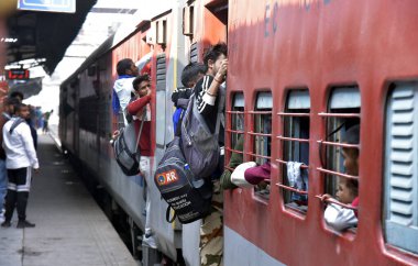 GHAZIABAD, INDIA - 17 Şubat 2025 'te Ghaziabad, Hindistan' da Ghaziabad Junction tren istasyonundaki kalabalık birbirlerini trene binmeye ve hareket halindeki trene tutunmaya zorluyor.. 