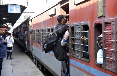 GHAZIABAD, INDIA - 17 Şubat 2025 'te Ghaziabad, Hindistan' da Ghaziabad Junction tren istasyonundaki kalabalık birbirlerini trene binmeye ve hareket halindeki trene tutunmaya zorluyor.. 