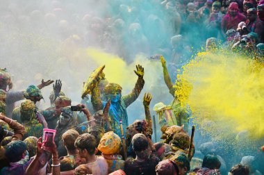 İnsanlar 9 Mart 2025 'te Hindistan' ın Mathura kentinde Nandji Tapınağı 'ndaki Lathmar Holi festivali sırasında birbirlerine renkli pudra sürerler.. 