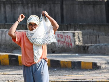 NOIDA, INDIA - 26 Mart 2025 'te Delhi-NCR' de sıcaklık artarken, 38. bölgedeki sıcaklıktan kaçmak için banliyö sakinleri başlarını örtüyor. Delhi bu sezonun en sıcak gününü 25 Mart Salı günü kaydetti.)