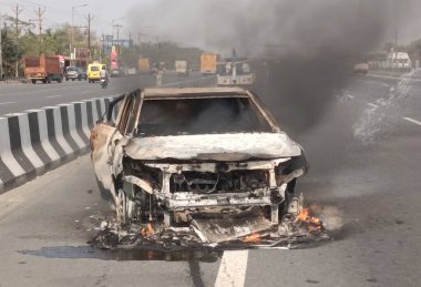 GHAZIABAD, INDIA - 26 Mart 2025 'te Delhi Meerut Otoyolu' nda, bir arabanın lastikleri patladıktan sonra hasar gören bir Baleno arabası aniden alev aldı ve 26 Mart 2025 'te Hindistan' ın Gaziabad kentinde tüm araba alev aldı.. 