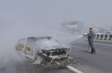 GHAZIABAD, INDIA - 26 Mart 2025 'te Delhi Meerut Otoyolu' nda, bir arabanın lastikleri patladıktan sonra hasar gören bir Baleno arabası aniden alev aldı ve 26 Mart 2025 'te Hindistan' ın Gaziabad kentinde tüm araba alev aldı.. 