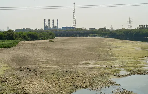 NEW DELHI, INDIA - 26 Mart 2025: nehir yatağı görülebilir ve Yamuna 'nın 26 Mart 2025' te Yeni Delhi, Hindistan 'da kuruduğunu gören ITO barajı boyunca akan sadece küçük bir dere. Yeni BJP hükümet gündeminin merkezinde Yamuna 'nın temizlenmesi yer alıyor.