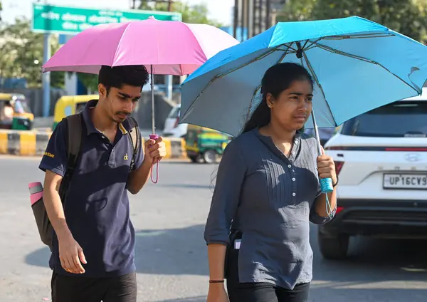 NOIDA, INDIA - 26 Mart 2025 'te Delhi-NCR' de sıcaklık artarken, 38. bölgedeki sıcaklıktan kaçmak için banliyö sakinleri başlarını örtüyor. Delhi bu sezonun en sıcak gününü 25 Mart Salı günü kaydetti.)