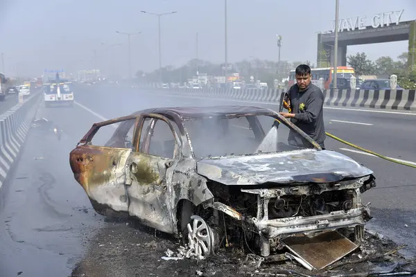GHAZIABAD, INDIA - 26 Mart 2025 'te Delhi Meerut Otoyolu' nda, bir arabanın lastikleri patladıktan sonra hasar gören bir Baleno arabası aniden alev aldı ve 26 Mart 2025 'te Hindistan' ın Gaziabad kentinde tüm araba alev aldı.. 
