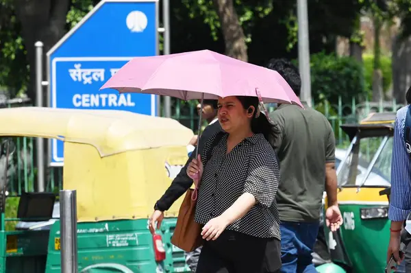 NEW DELHI, INDIA - 26 Mart 2025: Yeni Delhi, Hindistan 'da 26 Mart 2025 tarihinde, sıcak öğleden sonra Connaught Place' de günlük banliyö. Delhi bu sezonun en sıcak gününü kaydetti, maksimum sıcaklık 37,1 dereceye yükseldi..