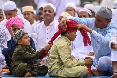KOLKATA, INDIA - 31 Mart 2025 'te Kızıl Yol' da Ramazan ayının sona ermesi münasebetiyle Kurban Bayramı özel sabah namazında (namaz) bir gencin türban bağlamasına yardım ediyor.