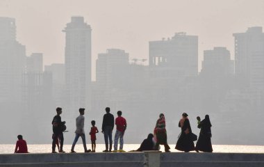 Vatandaşlar, 2 Nisan 2025 'te Mumbai, Hindistan' da, Marine Drive 'da sisli bir havada, şehirle dolu bir akşamın tadını çıkarıyorlar.