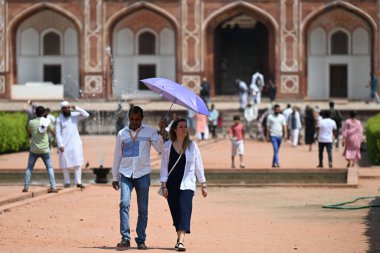 NEW DELHI, INDIA - 6 Nisan 2025 tarihinde Hindistan 'ın Yeni Delhi kentinde sıcak yaz öğleden sonra, Humayun Mezarı' nda kendilerini güneş ışığından koruyan turistler görülüyor.. 
