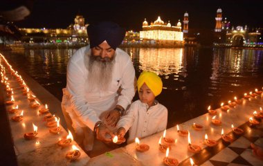 AMRITSAR, INDIA - 13 Nisan 2025: Müritler, 13 Nisan 2025 'te Hindistan' ın Amritsar kentinde, Altın Tapınak 'taki Baisakhi münasebetiyle mum ve gaz lambası yakarlar. Vaisakhi, diğer adıyla Baisakhi, Vaisakh ayının başlangıcını müjdeliyor..