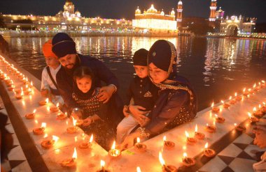 AMRITSAR, INDIA - 13 Nisan 2025: Müritler, 13 Nisan 2025 'te Hindistan' ın Amritsar kentinde, Altın Tapınak 'taki Baisakhi münasebetiyle mum ve gaz lambası yakarlar. Vaisakhi, diğer adıyla Baisakhi, Vaisakh ayının başlangıcını müjdeliyor..