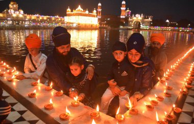 AMRITSAR, INDIA - 13 Nisan 2025: Müritler, 13 Nisan 2025 'te Hindistan' ın Amritsar kentinde, Altın Tapınak 'taki Baisakhi münasebetiyle mum ve gaz lambası yakarlar. Vaisakhi, diğer adıyla Baisakhi, Vaisakh ayının başlangıcını müjdeliyor..