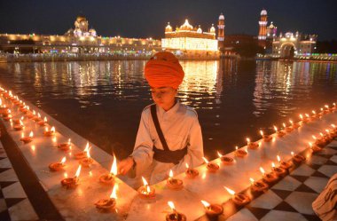 AMRITSAR, INDIA - 13 Nisan 2025: Müritler, 13 Nisan 2025 'te Hindistan' ın Amritsar kentinde, Altın Tapınak 'taki Baisakhi münasebetiyle mum ve gaz lambası yakarlar. Vaisakhi, diğer adıyla Baisakhi, Vaisakh ayının başlangıcını müjdeliyor..