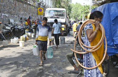 NEW DELHI, INDIA - 27 Nisan 2025 'te Hindistan' ın Yeni Delhi kentinde, Vivekanand Camp, Chanakyapuri 'de devam eden su krizinin ortasında, sıcak bir yaz gününde insanlar bir NDMC tankerinden su topluyor.. 