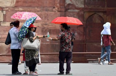 YENİ DELHI, INDIA - 26 Nisan 2025 tarihinde, insanlar kendilerini sıcak öğleden sonra, Kızıl Kale 'de, Yeni Delhi, Hindistan' da, sert güneş ışığından korurken görülüyor.