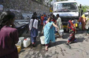 NEW DELHI, INDIA - 27 Nisan 2025 'te Hindistan' ın Yeni Delhi kentinde, Vivekanand Camp, Chanakyapuri 'de devam eden su krizinin ortasında, sıcak bir yaz gününde insanlar bir NDMC tankerinden su topluyor.. 