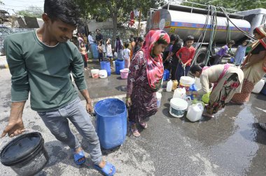 NEW DELHI, INDIA - 27 Nisan 2025 'te Hindistan' ın Yeni Delhi kentinde, Vivekanand Camp, Chanakyapuri 'de devam eden su krizinin ortasında, sıcak bir yaz gününde insanlar bir NDMC tankerinden su topluyor.. 