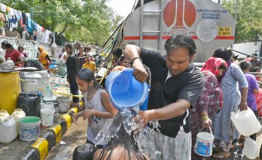 NEW DELHI, INDIA - 27 Nisan 2025 'te Hindistan' ın Yeni Delhi kentinde, Vivekanand Camp, Chanakyapuri 'de devam eden su krizinin ortasında, sıcak bir yaz gününde insanlar bir NDMC tankerinden su topluyor.. 