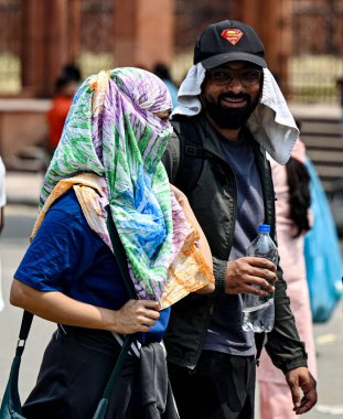 YENİ DELHI, INDIA - 26 Nisan 2025 tarihinde, insanlar kendilerini sıcak öğleden sonra, Kızıl Kale 'de, Yeni Delhi, Hindistan' da, sert güneş ışığından korurken görülüyor.