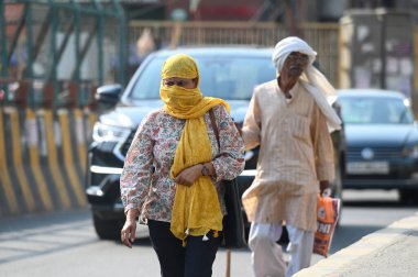 NOIDA, INDIA - 27 Nisan - Delhi-NCR 'de sıcaklık artarken, Hindistan' ın Noida şehrinde 27 Nisan 2025 'te 38A sektöründeki sıcaktan kaçmak için banliyö sakinleri başlarını örtüyor. En yüksek sıcaklık 41 derece civarındaydı ve en düşük sıcaklık da etraftaydı. 