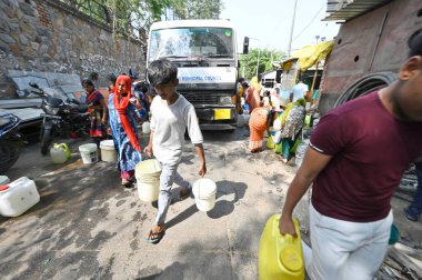 NEW DELHI, INDIA - 27 Nisan 2025 'te Hindistan' ın Yeni Delhi kentinde, Vivekanand Camp, Chanakyapuri 'de devam eden su krizinin ortasında, sıcak bir yaz gününde insanlar bir NDMC tankerinden su topluyor.. 