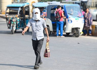 NOIDA, INDIA - 27 Nisan - Delhi-NCR 'de sıcaklık artarken, Hindistan' ın Noida şehrinde 27 Nisan 2025 'te 38A sektöründeki sıcaktan kaçmak için banliyö sakinleri başlarını örtüyor. En yüksek sıcaklık 41 derece civarındaydı ve en düşük sıcaklık da etraftaydı. 