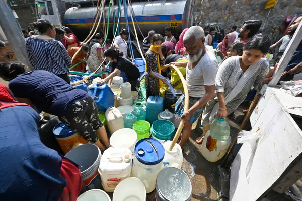 NEW DELHI, INDIA - 27 Nisan 2025 'te Hindistan' ın Yeni Delhi kentinde, Vivekanand Camp, Chanakyapuri 'de devam eden su krizinin ortasında, sıcak bir yaz gününde insanlar bir NDMC tankerinden su topluyor.. 