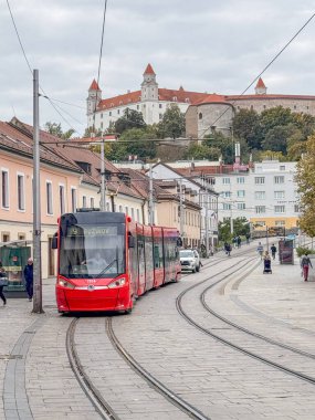 Bratislava Eski Kasabası, Slovakya 'da arka planda Bratislava Kalesi' ni gösteren kırmızı bir tramvay geziyor.