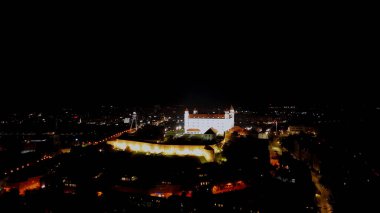 Aerial drone night photo of Bratislava Castle in Bratislava, Slovakia. The Bratislava Castle sits high above the Slovakian capital city of Bratislava and the Danube River. When visiting the castle, you can enjoy amazing views of the city. clipart