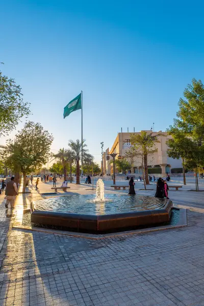 Arka planda Suudi bayrağı olan bir Riyad Çeşmesi Günbatımı Manzarası. Çeşme, Suudi Arabistan 'ın Riyad ilinin Ad Dirah ilçesinde Al-Safat Meydanı yakınlarında yer almaktadır. Günbatımı Suudi bayrağı için güzel bir zemin sağlar..