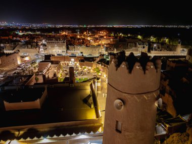Shaqra 'nın hava gece drone görüntüsü aydınlatılmış şehir manzaraları, tarihi Najdi mimarisi ve önemli kültürel simgeler.