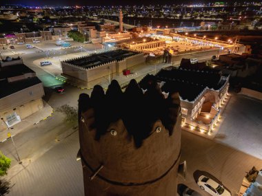 Shaqra 'nın hava gece drone görüntüsü aydınlatılmış şehir manzaraları, tarihi Najdi mimarisi ve önemli kültürel simgeler.