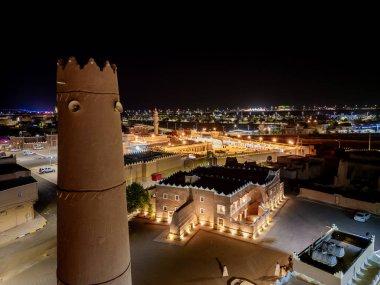 Shaqra 'nın hava gece drone görüntüsü aydınlatılmış şehir manzaraları, tarihi Najdi mimarisi ve önemli kültürel simgeler.