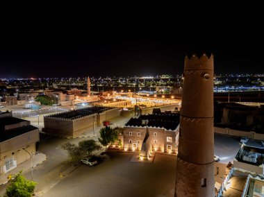 Shaqra 'nın hava gece drone görüntüsü aydınlatılmış şehir manzaraları, tarihi Najdi mimarisi ve önemli kültürel simgeler.