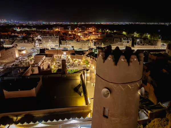 Shaqra 'nın hava gece drone görüntüsü aydınlatılmış şehir manzaraları, tarihi Najdi mimarisi ve önemli kültürel simgeler.