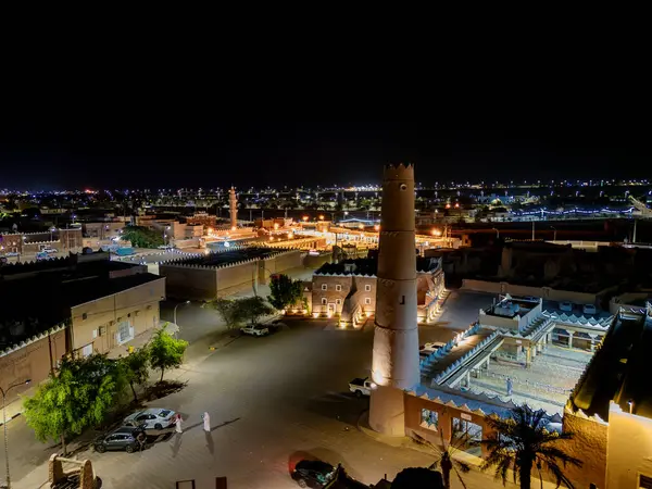 Shaqra 'nın hava gece drone görüntüsü aydınlatılmış şehir manzaraları, tarihi Najdi mimarisi ve önemli kültürel simgeler.