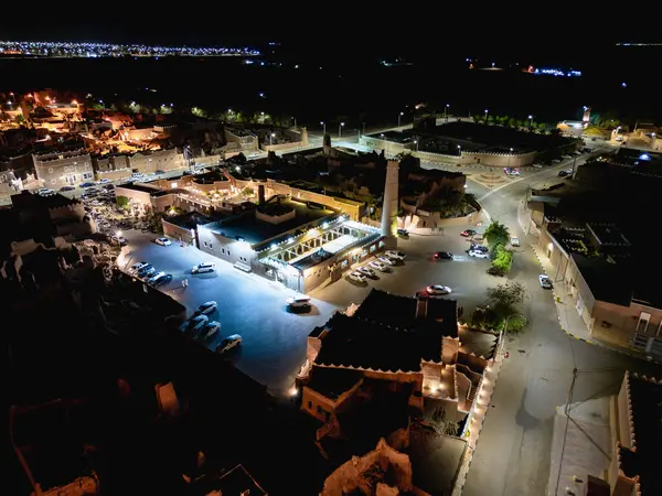 Shaqra 'nın hava gece drone görüntüsü aydınlatılmış şehir manzaraları, tarihi Najdi mimarisi ve önemli kültürel simgeler.