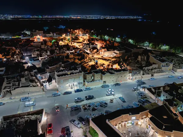 Shaqra 'nın hava gece drone görüntüsü aydınlatılmış şehir manzaraları, tarihi Najdi mimarisi ve önemli kültürel simgeler.