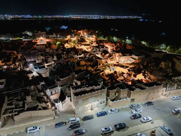 Shaqra 'nın hava gece drone görüntüsü aydınlatılmış şehir manzaraları, tarihi Najdi mimarisi ve önemli kültürel simgeler.