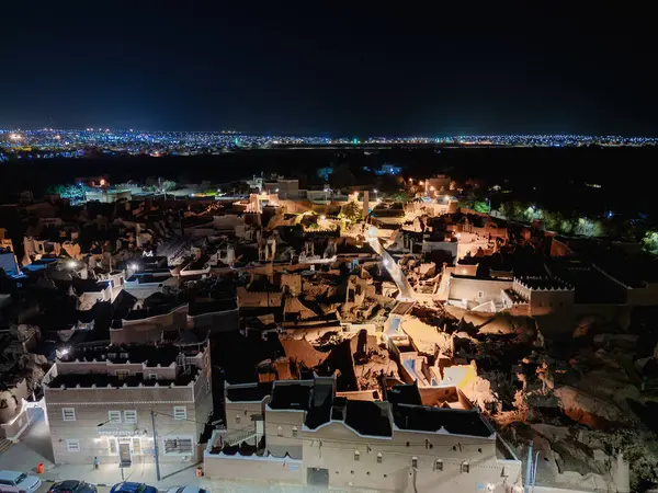 Shaqra 'nın hava gece drone görüntüsü aydınlatılmış şehir manzaraları, tarihi Najdi mimarisi ve önemli kültürel simgeler.