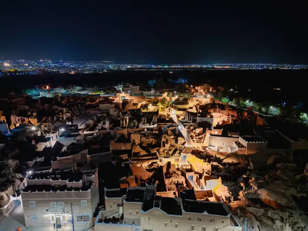 Shaqra 'nın hava gece drone görüntüsü aydınlatılmış şehir manzaraları, tarihi Najdi mimarisi ve önemli kültürel simgeler.