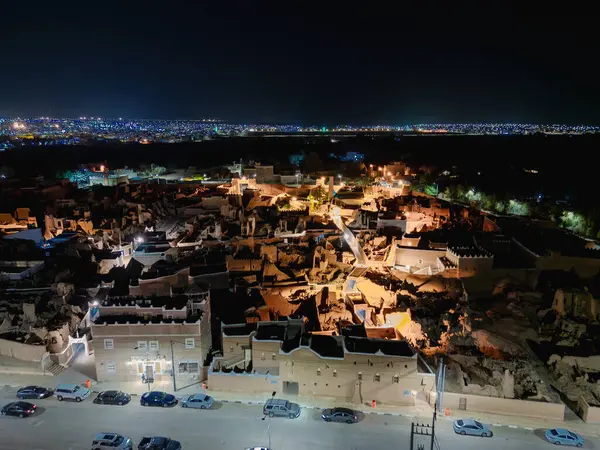 Shaqra 'nın hava gece drone görüntüsü aydınlatılmış şehir manzaraları, tarihi Najdi mimarisi ve önemli kültürel simgeler.