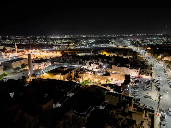 Shaqra 'nın hava gece drone görüntüsü aydınlatılmış şehir manzaraları, tarihi Najdi mimarisi ve önemli kültürel simgeler.