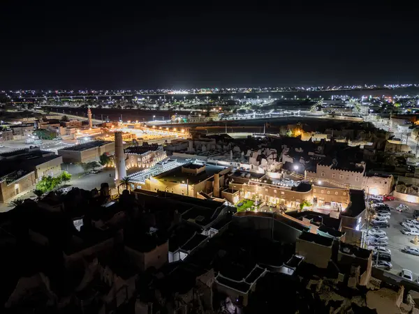 Shaqra 'nın hava gece drone görüntüsü aydınlatılmış şehir manzaraları, tarihi Najdi mimarisi ve önemli kültürel simgeler.