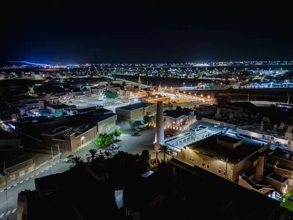 Shaqra 'nın hava gece drone görüntüsü aydınlatılmış şehir manzaraları, tarihi Najdi mimarisi ve önemli kültürel simgeler.