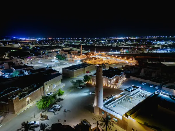 Shaqra 'nın hava gece drone görüntüsü aydınlatılmış şehir manzaraları, tarihi Najdi mimarisi ve önemli kültürel simgeler.