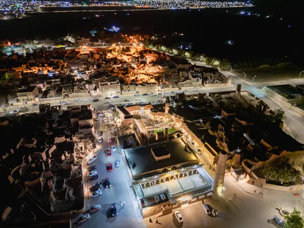 Shaqra 'nın hava gece drone görüntüsü aydınlatılmış şehir manzaraları, tarihi Najdi mimarisi ve önemli kültürel simgeler.