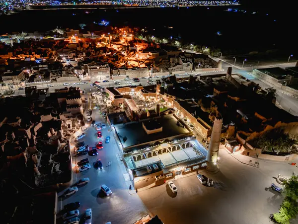 Shaqra 'nın hava gece drone görüntüsü aydınlatılmış şehir manzaraları, tarihi Najdi mimarisi ve önemli kültürel simgeler.